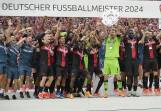 Leverkusen goalkeeper Lukas Hradecky hoists the Bundesliga trophy surrounded by teammates. (AP PHOTO)